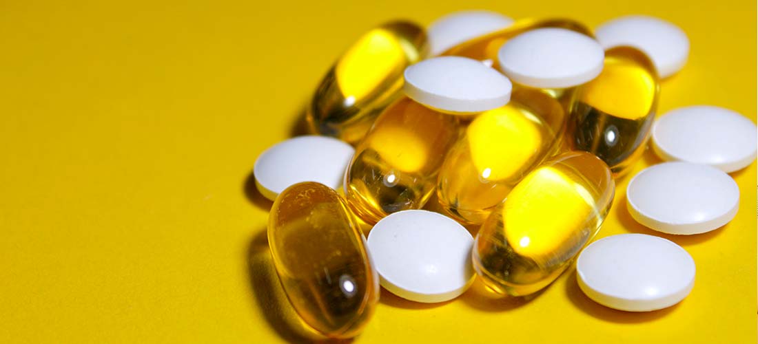 белые таблетки и желтые капсулы на желтом фоне