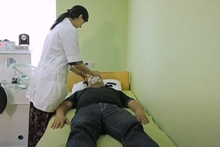 Пациент лежит на кровати, а врач стоит возле него